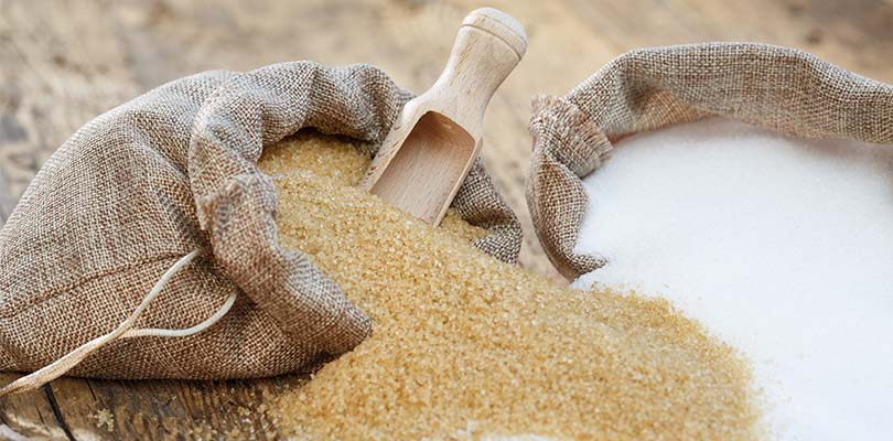 A bag of raw sugar and refined sugar spill out of their bags